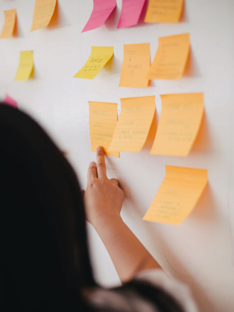 Post Its on a wall and a woman touching one with her hand